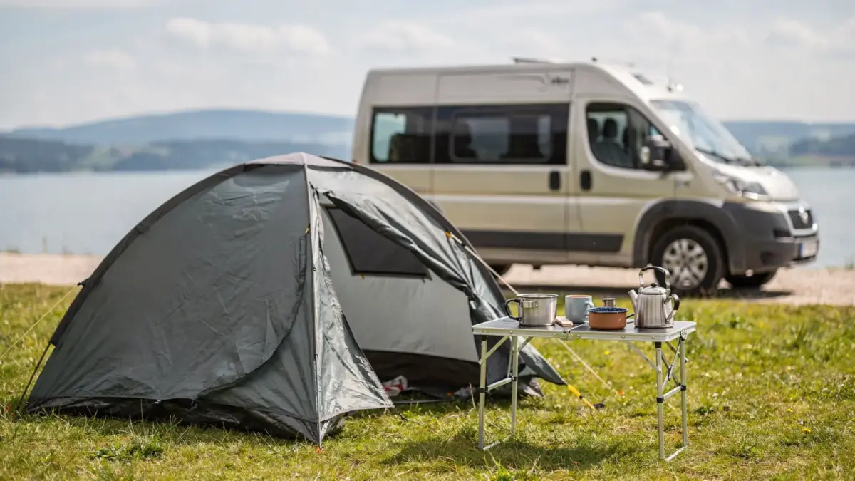 Ordentliches Bodensee-Camping mit Zelt, Campingtisch und Wohnmobil zum Thema Kosten sparen