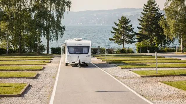 Wohnwagen auf der Anfahrt zum Campingplatz am Bodensee mit See im Hintergrund